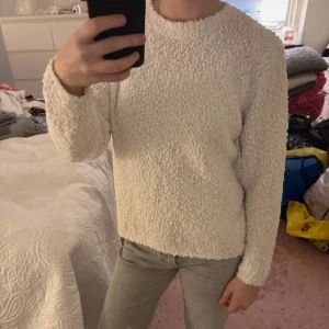Vit fluffig tröja med lång ärm - Supermjuk och fluffig vit tröja med lång ärm och rund hals. Perfekt för kalla dagar när du vill vara extra cozy. Tröjan har en oversized känsla och är tillverkad i ett mysigt teddy-liknande material.