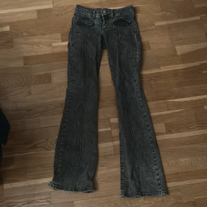 Svarta bootcut jeans med fickor - Snygga svarta bootcut jeans med tvättad look och markerade sömmar. Byxorna har stora fickor framtill och klassisk knapp- och dragkedjestängning. Perfekta för dig som gillar en retro vibe och vill sticka ut lite extra.