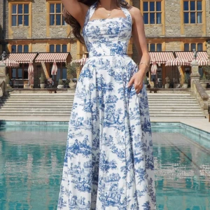 Vit och blå långklänning med snörning - Superfin långklänning i vit bomull med blått, romantiskt mönster. Klänningen har halterneck, markerad midja och snörning i ryggen för perfekt passform. Den vida kjolen ger en lyxig känsla och passar perfekt för sommarens alla tillfällen.