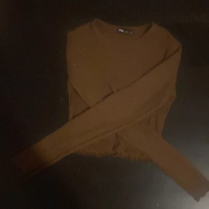 Brun långärmad tröja från FB Sister - Säljer en brun långärmad tröja från FB Sister i storlek S. Tröjan har en enkel, rund halsringning och råa kanter nertill för en lite edgy look. Perfekt att matcha med jeans eller kjol för en chill stil.