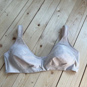 Beige linnetopp från Trofé 85C - Säljer en beige linnetopp från Trofé i storlek 85C. Toppen har breda axelband och diskret blommönster i tyget. Tillverkad i mjuk polyesterblandning som känns skön mot huden. Perfekt för dig som vill ha en enkel och stilren look.