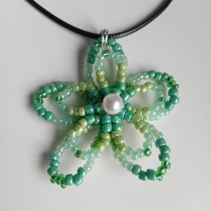 Halsband med pärlblomma i grönt - Unikt halsband med en handgjord blomma av gröna pärlor. Kedjan är justerbar 