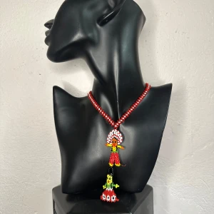 Vintagehalsband med pärlade figurer – färgstark folk art  - Unikt vintagehalsband i glaspärlor med två handgjorda figurer som hänge. Halsbandet är ca 60 cm långt, ca 0,8 cm brett, med ett hänge på ca 10 cm. Röd- och vitspiral i kedjan, figurer i klara färger – ett uttrycksfullt statementsmycke i folkloristisk stil. Sannolikt från de senaste decennierna. I mycket fint skick utan saknade pärlor.  Ingen prutning, men jag erbjuder gärna bundlerrabatt. Rensar smyckesskrinet – kika gärna på mina andra annonser också!  