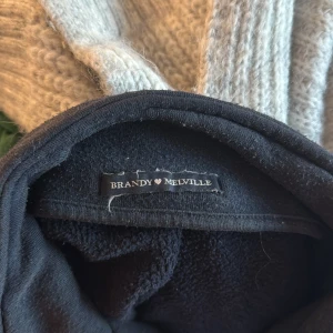 Mörkblå half zip hoodie Brandy Melville - Mörkblå hoodie från Brandy Melville med half zip och broderad amerikansk flagga samt texten 'Los Angeles 1984' på bröstet. Tröjan har hög krage, lång ärm och är i mjukt, fleeceliknande material. Perfekt för en chill och avslappnad stil.