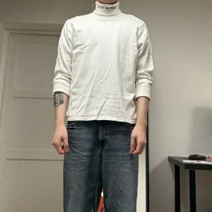 Vit polotröja från Ripndip - Säljer en clean vit polotröja från Ripndip med texten 'MUST be NICE' broderad på kragen. Tröjan har lång ärm och normal passform, perfekt att styla med jeans eller under en jacka. Mjuk bomullskänsla och enkel att matcha med allt.