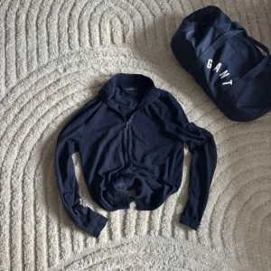 Mörkblå kofta från Hampton Republic - Mörkblå kofta från Hampton Republic i klassisk stil med hel dragkedja framtill och hög krage. Långärmad och tillverkad i mjukt bomullsmaterial, perfekt för lager-på-lager. Enkel och stilren design som funkar till det mesta.