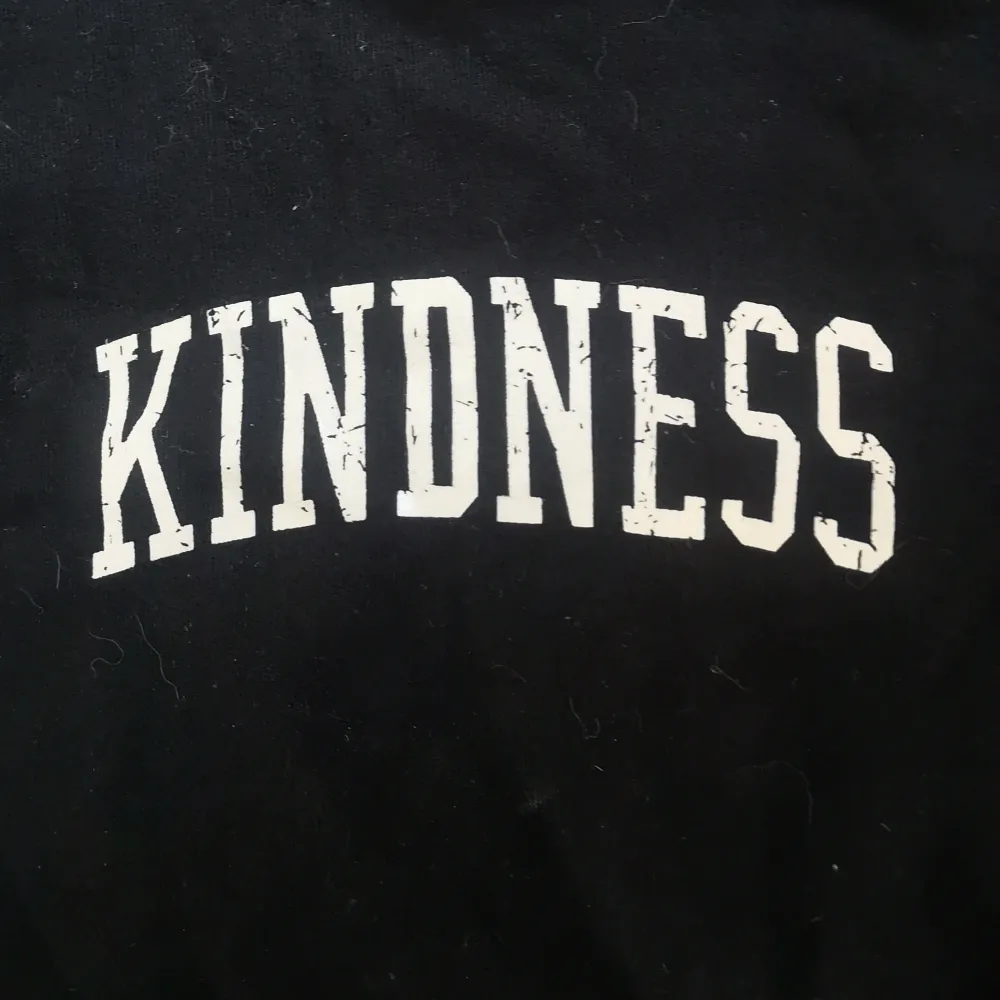 Säljer en svart hoodie med texten 'Kindness' tryckt i vitt på bröstet. Tröjan har en klassisk design med huva och långa ärmar. Perfekt för en avslappnad stil eller när man bara vill mysa eller sova.🥰. Hupparit & Collegepaidat.