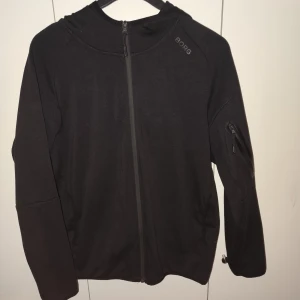 Svart hoodie  från Björn Borg - Säljer en stilren svart zip hoodie från Björn Borg med dragkedja framtill och en praktisk ficka med dragkedja på ärmen. Perfekt för en sportig look eller vardagsbruk.
