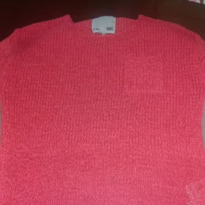 Rosa stickad tröja från 157 - Säljer en härlig rosa stickad tröja från 157. Tröjan har en enkel design med en liten bröstficka och rund halsringning. Perfekt för en avslappnad stil. 🌸