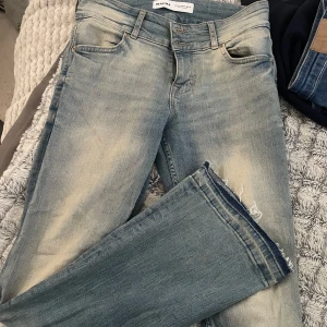 Blå jeansbyxor från Bershka - Snygga blå jeansbyxor från Diesel med en sliten look och fransiga kanter. 