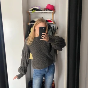 Mörkgrå stickad tröja från Vero Moda - Säljer en snygg mörkgrå stickad tröja från Vero Moda. Tröjan har långa puffärmar och en ribbad struktur som ger en trendig look. Perfekt för kyligare dagar!