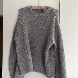 Grå stickad tröja från H&M Divided - Mysig grå stickad tröja från H&M Divided. Perfekt för kyliga dagar med sin mjuka och texturerade yta. Tröjan har en avslappnad passform och långa ärmar.