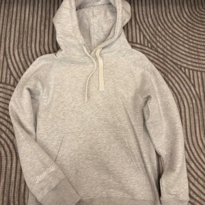 Grå hoodie från Russemerch - Säljer en stilren grå hoodie från Russedress. Den har en klassisk design med en stor ficka framtill och justerbar huva med snören. Perfekt för en avslappnad stil.
