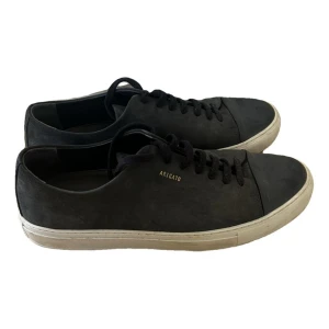 Marinblå sneakers från Axel Arigato - Snygga svarta sneakers från Axel Arigato med vit sula och diskret logga på sidan. Perfekta för en stilren look. Skorna har klassisk snörning och är tillverkade i skinn.