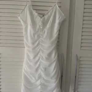 Vit klänning från H&M Divided - vit klänning från H&M Divided. Klänningen har smala axelband och en snygg rynkad design framtill. Perfekt för sommarens alla tillfällen. 💫 knappt använd och har inga defekter!