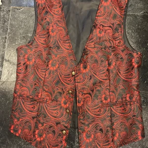 Röd och svart goth väst  - Snygg väst med ett iögonfallande rött och svart mönster. Västen har knappar framtill och en klassisk passform. Perfekt för att ge en färgklick till din outfit.
