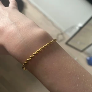 Guldarmband med tvinnad design - Elegant guldarmband med en fin tvinnad design. Perfekt för att lägga till en touch av stil till vilken outfit som helst. Enkel och tidlös.