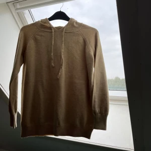 Beige merinoull hoodie - Säljer en stilren beige merinoull hoddie som har krympt rätt rejält. Den är liten på mig som är 176. Mått: längd 52cm ,  bredd 36cm ,  Armar: 52cm 