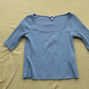 Blå ribbad topp - Säljer en stilren blå ribbad topp med trekvartsärm. Perfekt för en avslappnad look. Toppen har en fyrkantig halsringning som ger en modern touch. Använd endast en gång💕💕