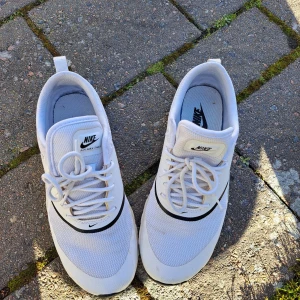 Vita Nike Air Max sneakers - Snygga vita Nike Air Max sneakers med klassisk design och svart swoosh. Skorna har snörning och en bekväm sula med synlig Air Max-dämpning för extra komfort. Använda sparsamt. 