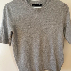 Grå fin stickad tröja från Lager 157 storlek XS - Säljer en stilren grå stickad tröja från Lager 157. Tröjan har korta ärmar och en rund halsringning. Passar till många olika outfits och tillfällen.