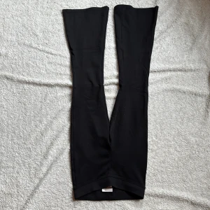 Svarta utsvängda leggings från Gina Tricot - Snygga svarta leggings från Gina Tricot. Perfekta för en stilren look och kan matchas med olika toppar. De är bekväma och stretchiga, vilket gör dem idealiska för både vardag och avslappnade tillfällen.