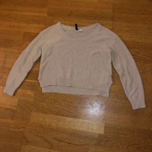 Beige stickad tröja - Säljer en beige stickad tröja med rund hals och långa ärmar. Tröjan har ribbade muddar vid ärmslut och nederkant, vilket ger en snygg och bekväm passform. Perfekt för kyligare dagar!