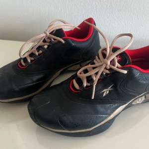 Svarta sneakers från Reebok - Reebok sneakers med röda detaljer och beige snörning. Storlek 35,5. Bra skick!