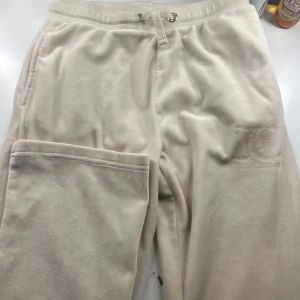 Beige mjukisbyxor från Juicy Couture - Säljer ett par superbekväma beige mjukisbyxor från Juicy Couture. Byxorna har en elastisk midja med snörning och två bakfickor. Säljer dessa för mindre pris för dom är mer urtvättade!
