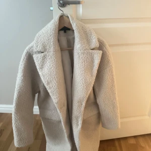 Beige teddyjacka från KappAhl - Säljer en mysig beige teddyjacka från KappAhl. Jackan har en klassisk design med bred krage och är perfekt för kyliga dagar. Den är långärmad och har en mjuk, fluffig yta som ger en trendig look.