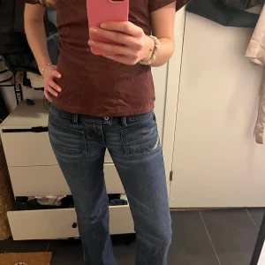 Blå jeans från Diesel - Snygga blå jeans från Diesel med en klassisk femficksdesign och en diskret logga på fickan. Jeansen har en bootcut-stil som ger en avslappnad look. Perfekta för en casual outfit.
