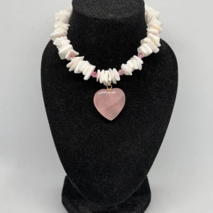 Armband med rosa hjärthänge - Charmigt armband med vita pärlor och ett stort rosa hjärthänge. Perfekt för att ge en romantisk touch till din outfit. Pärlorna är oregelbundet formade vilket ger en unik look. Lite större omfång på detta armband. 