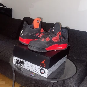 Air Jordan 4s  - Säljer ett par snygga svarta och röda Nike Air Jordans med klassisk design. Skorna har snörning och en iögonfallande röd detalj på sidorna. Perfekta för dig som vill ha en stilren och sportig look. Red thunder köpta för 6000kr mitt pris är 3500kr