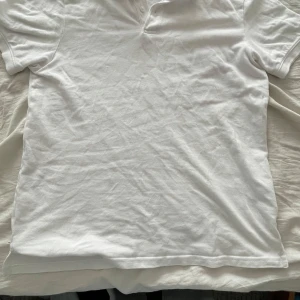 Vit pikétröja från H&M, storlek S - Klassisk vit pikétröja från H&M i regular fit. Tröjan har korta ärmar, krage och knäppning framtill. Tillverkad i 100% bomull vilket gör den mjuk och skön att bära. Perfekt till en avslappnad och stilren look.