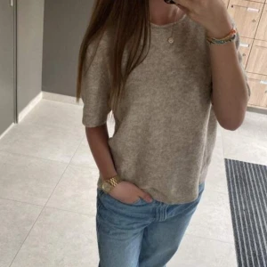 Beige stickad kortärmad tröja - Supermjuk och basic beige stickad tröja med korta ärmar och rund hals. Tröjan har en avslappnad passform och ribbade kanter vid ärmslut och nederkant. Perfekt att styla med jeans eller kjol för en chill look. Så gott som ny, endast testad💕