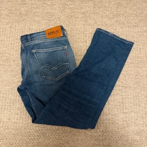 Replay Grover blå jeans straight fit - Säljer ett par Replay Grover jeans i klassisk blå tvätt med straight fit. Jeansen har fem fickor, snygga slitningar och detaljerad söm på bakfickan. Perfekta för dig som gillar en tidlös look och vill ha jeans med skön passform.