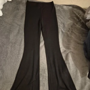 Svarta bootcut byxor från H&M Divided XS - Svarta bootcut byxor från H&M Divided i storlek XS. Byxorna har hög midja och är gjorda i ett stretchigt material med viskos, polyamid och elastan. Snygg passform som sitter tajt upptill och släpper ut vid bensluten.