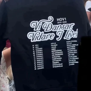 SÖKER!!!! Svart Hov1 hoodie Vi Dansar Vidare HELST STORLEK S-M - SÖKER!! Svart hoodie från Hov1 med stor vit text på ryggen: 'Vi Dansar Vidare I Livet' och turnédatum samt städer listade under. Klassisk passform med huva och långa ärmar. Perfekt för dig som älskar svensk musik och vill ha en snygg merchtröja.