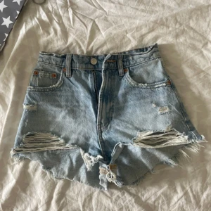 Ljusa jeansshorts från Zara - Snygga ljusblå jeansshorts från Zara med hög midja, slitna detaljer och fransig kant. Knappt andvända