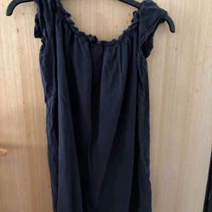 Mörkblå kortklänning från Pull&Bear - Supersöt mörkblå kortklänning från Pull&Bear med rynkade detaljer vid halsringningen och axlarna. Klänningen har en avslappnad passform och är tillverkad i mjuk bomull, perfekt för en chill och stilren look.