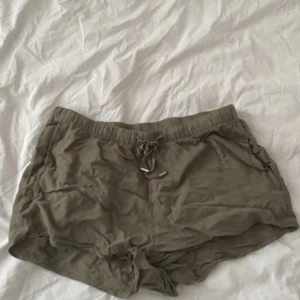 Gröna shorts med snörning från H&M - Snygga gröna shorts från H&M Divided i storlek 36. De har elastisk midja med snörning och är tillverkade i mjuk viskos som känns skön mot huden. Perfekta för varma sommardagar och chill häng. Enkla att matcha med allt i garderoben.