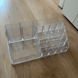 Transparent sminkförvaring  - Snygg och praktisk sminkförvaring i genomskinlig akryl med flera fack i olika storlekar. Perfekt för att organisera läppstift, borstar och andra sminkprodukter på sminkbordet. Stilren design som passar in i alla rum. Den har repor som man ser på bilderna men funkar super endå 