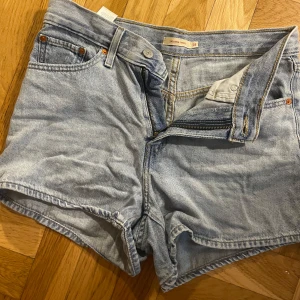Levi's 80s Mom Shorts ljusblå jeans - Snygga 80s Mom Shorts från Levi's i ljusblå denim. Klassisk femficksmodell med hög midja, dragkedja och knapp framtill. Perfekt retro vibe och riktigt skön passform. Ikonisk Levi's-patch baktill och slitstarkt jeanstyg.