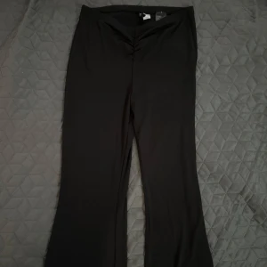 Utsvänga tights/byxor. - Svarta utsvängda med snygg v-ringad midja och lätt rynk framtill. Byxorna har en figurnära passform upptill och vida ben nertill. Perfekta för dig som gillar en stilren och trendig look. Storlek M.