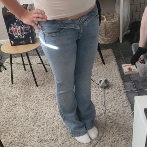 Ljusblå bootcut jeans - Säljer ett par ljusblå jeans med bootcut passform och ganska låg midja. Jeansen har klassisk femficksdesign och är tillverkade i mjukt denimtyg. Perfekta för dig som gillar en avslappnad och retro vibe.