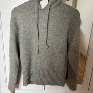 Grå stickad hoodie med huva - Väldigt efterfrågad mysig grå stickad hoodie med huva och snörning. Tröjan har långa ärmar och bred ribbad mudd vid ärmslut och nederkant. Perfekt för kyliga dagar och enkel att matcha med jeans eller mjukisbyxor. Har slutat säljas så passa på! Priset är diskuterbart💕