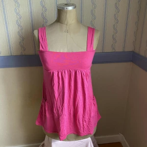 Rosa linnetopp med breda axelband - Supersöt rosa linnetopp med breda axelband och lös passform. Toppen har rynkad nederdel och två fickor fram. Ingen storlek, men uppskattas till S-M. 🩷