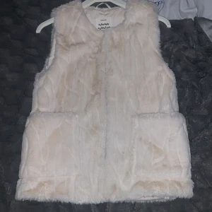 Vit pälsväst från Zara Kids - Supermjuk och fluffig vit pälsväst från Zara Kids Outerwear Collection. Västen har två stora fickor framtill och är helfodrad för extra komfort. Perfekt att slänga över en hoodie eller långärmad tröja för en cool och mysig look. Och vi kan prata om priset om det behövs! 