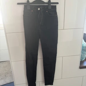 Svarta skinny jeans med hög midja - Köpta på BIKBOK. Snygga svarta skinny jeans med hög midja och klassiska fyra fickor. Jeansen har dragkedja och knapp framtill och är tillverkade i stretchigt material för en tight passform. Perfekta till sneakers eller boots. Storlek S. köparen står för frakt. 