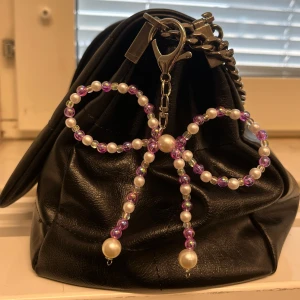 Charmed Keychains  - Accessorize your accessories med Charmed Keychains. Pynta din väska, nyckelring mm med våra rosett formade nyckelringar. Lila och vit.